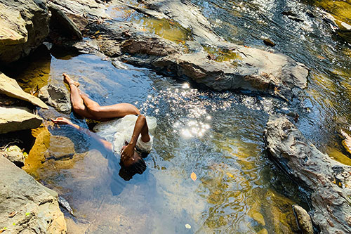 women laying on rocks in river